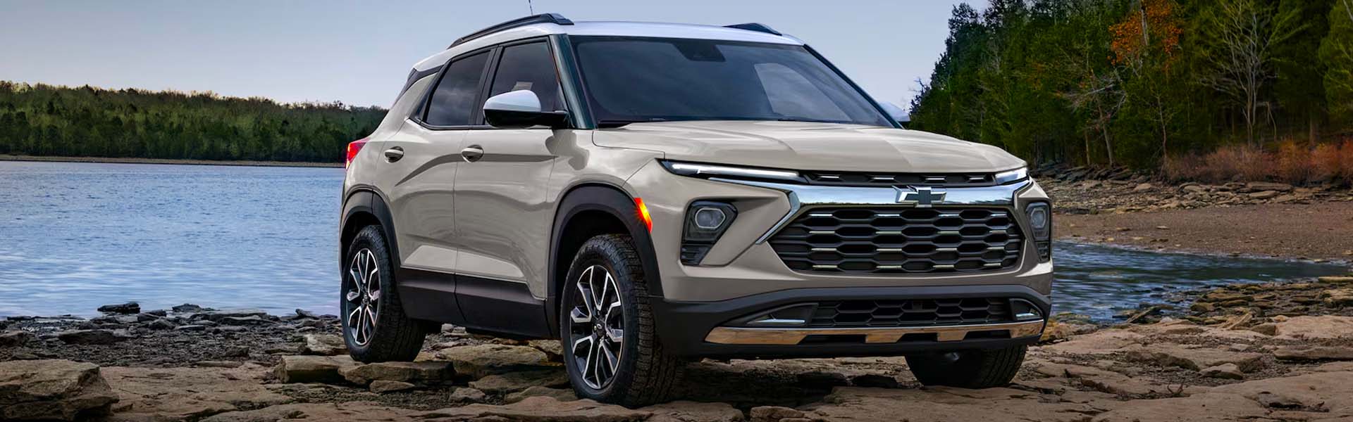 2026 Chevrolet Trailblazer parked near a rocky shoreline with a forest background.